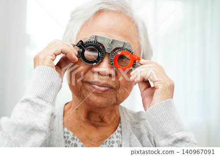 Optometrist checking Asian elderly woman ophthalmic vision eye test and using optical trial frame. Optometrist checking Asian elderly woman ophthalmic vision eye test and using optical trial frame. 140967091