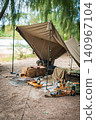 A military-style solo camping tent nestled in a lush green, waterside location. 140967104