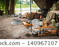 Enjoying a solo camping trip with bottle racks lined up under the canopy and a riverside location. 140967107