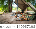 A panoramic view of a sophisticated military pup tent site blending seamlessly into the tranquil riverside forest. 140967108