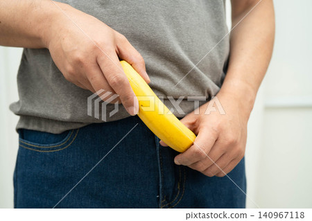 Male doctor stands holding a banana, penis health. Male doctor stands holding a banana, penis health. 140967118