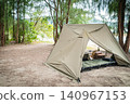 A pup tent site set up in a military style in a beautiful forest where sunlight filters through the trees. 140967153