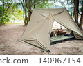 A stylish pup tent solo campsite functionally laid out in a wooded area by the water's edge, surrounded by abundant nature. 140967154