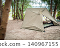 A military pup tent and a comfortably set-up cot are visible through the trees. 140967155