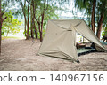 A rugged military-style pup tent and cot set up in the woods: a solo camping style. 140967156