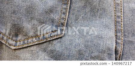 A close-up view of the back pocket of blue denim jeans, showing yellow stitching. A close-up view of the back pocket of blue denim jeans, showing yellow stitching. 140967217