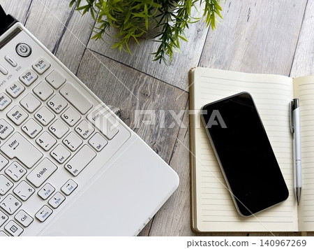 A minimalist workspace with a smartphone, notebook, and keyboard. A minimalist workspace with a smartphone, notebook, and keyboard. 140967269