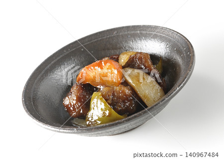 A single serving of sweet and sour pork with black vinegar, containing carrots, onions, bell peppers, and pork shoulder, photographed against a white background. 140967484