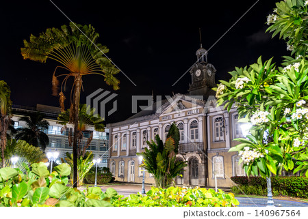 The illuminated facade of the historic Town Hall at night, surrounded by lush tropical gardens in Fort-de-France, Martinique. The illuminated facade of the historic Town Hall at night, surrounded by lush tropical gardens in Fort-de-France, Martinique. 140967564