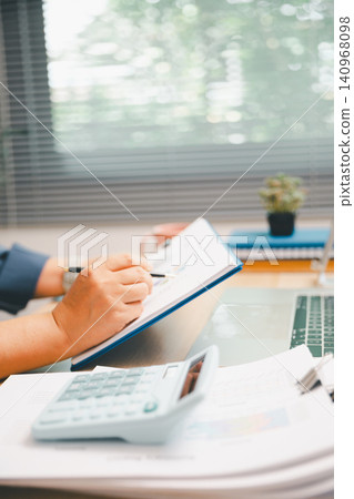Professional filling financial report on clipboard with calculator and laptop nearby, ideal for accounting, budget planning, audit review, business analysis, productivity, and office workflow. Professional filling financial report on clipboard with calculator and laptop nearby, ideal for accounting, budget planning, audit review, business analysis, productivity, and office workflow. 140968098