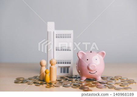 Family figures with pink piggy bank, coins and modern building model, symbolizing family savings, real estate investment, mortgage planning, and financial security. 140968189