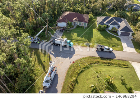 Electrician workers repairing damaged power lines using bucket trucks after hurricane in Florida residential area Electrician workers repairing damaged power lines using bucket trucks after hurricane in Florida residential area 140968294