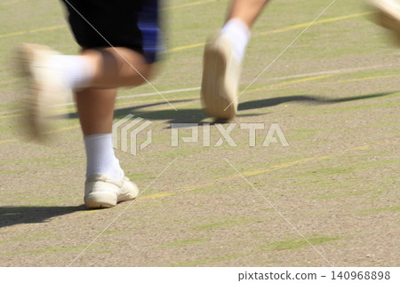 At the feet of students running on the school grounds during a foot race at an elementary school sports day. At the feet of students running on the school grounds during a foot race at an elementary school sports day. 140968898