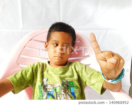 Determined Young Boy Raising His Fist with Serious Gaze Determined Young Boy Raising His Fist with Serious Gaze 140968952