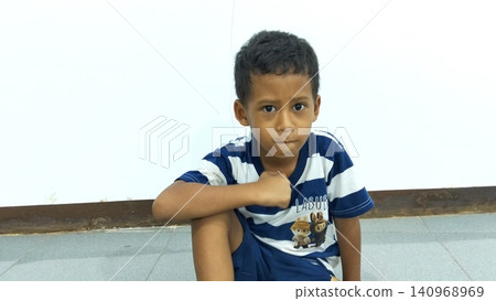 Determined Young Boy Raising His Fist with Serious Gaze Determined Young Boy Raising His Fist with Serious Gaze 140968969