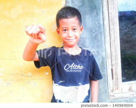 Determined Young Boy Raising His Fist with Serious Gaze Determined Young Boy Raising His Fist with Serious Gaze 140969004