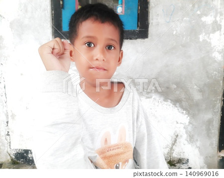 Determined Young Boy Raising His Fist with Serious Gaze Determined Young Boy Raising His Fist with Serious Gaze 140969016