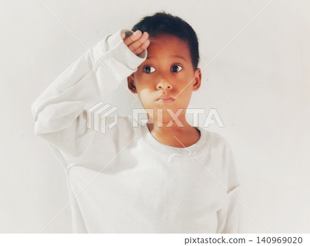 Determined Young Boy Raising His Fist with Serious Gaze Determined Young Boy Raising His Fist with Serious Gaze 140969020