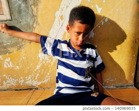 Determined Young Boy Raising His Fist with Serious Gaze 140969035