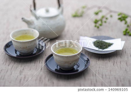 Enjoying green tea, expressing a moment of hospitality with white porcelain teacups and a teapot. Enjoying green tea, expressing a moment of hospitality with white porcelain teacups and a teapot. 140969105