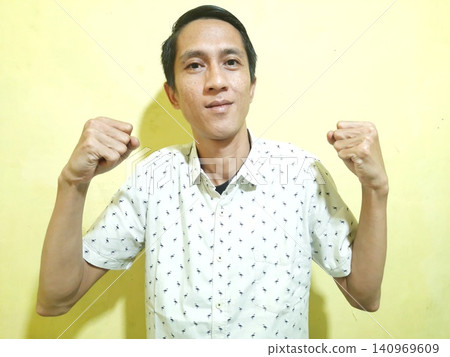 Young Asian Man Feeling Stressed with Headache Against Yellow Wall Young Asian Man Feeling Stressed with Headache Against Yellow Wall 140969609