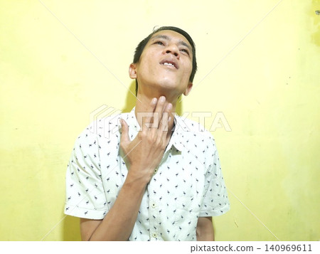 Young Asian Man Feeling Stressed with Headache Against Yellow Wall Young Asian Man Feeling Stressed with Headache Against Yellow Wall 140969611