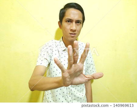 Young Asian Man Feeling Stressed with Headache Against Yellow Wall Young Asian Man Feeling Stressed with Headache Against Yellow Wall 140969613