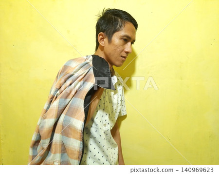 Young Asian Man Feeling Stressed with Headache Against Yellow Wall Young Asian Man Feeling Stressed with Headache Against Yellow Wall 140969623