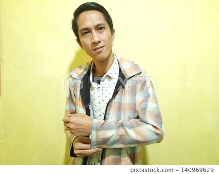 Young Asian Man Feeling Stressed with Headache Against Yellow Wall Young Asian Man Feeling Stressed with Headache Against Yellow Wall 140969629
