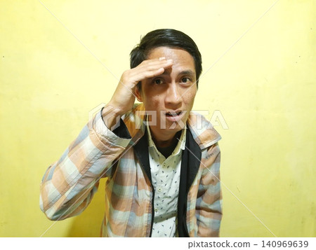 Young Asian Man Feeling Stressed with Headache Against Yellow Wall Young Asian Man Feeling Stressed with Headache Against Yellow Wall 140969639