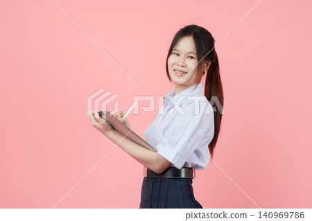 Portrait Thai student in uniform, Asian teen girl cute pretty cheerful happy smiling with tablet Portrait Thai student in uniform, Asian teen girl cute pretty cheerful happy smiling with tablet 140969786