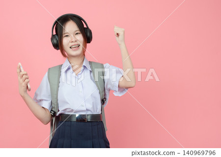 Student in uniform listening music from Smartphone with Headphone studio isolated pink background. Student in uniform listening music from Smartphone with Headphone studio isolated pink background. 140969796