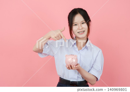 Portrait Thai student in uniform, Asian teen girl cute pretty cheerful happy smiling with piggy bank Portrait Thai student in uniform, Asian teen girl cute pretty cheerful happy smiling with piggy bank 140969801