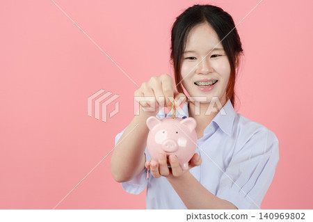 Portrait Thai student in uniform, Asian teen girl cute pretty cheerful happy smiling with piggy bank Portrait Thai student in uniform, Asian teen girl cute pretty cheerful happy smiling with piggy bank 140969802