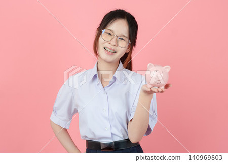 Portrait Thai student in uniform, Asian teen girl cute pretty cheerful happy smiling with piggy bank Portrait Thai student in uniform, Asian teen girl cute pretty cheerful happy smiling with piggy bank 140969803