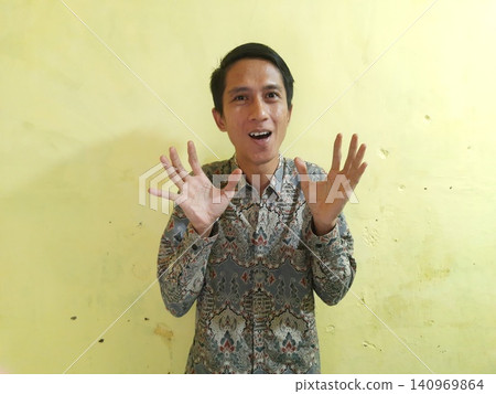 Energetic Asian Man in Batik Showing Hands with Surprised Expression 140969864