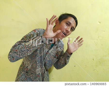 Energetic Asian Man in Batik Showing Hands with Surprised Expression 140969865