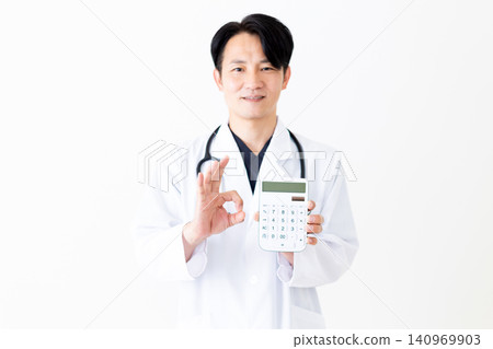 A middle-aged male doctor in a white coat holding a calculator and making a circular motion. A middle-aged male doctor in a white coat holding a calculator and making a circular motion. 140969903