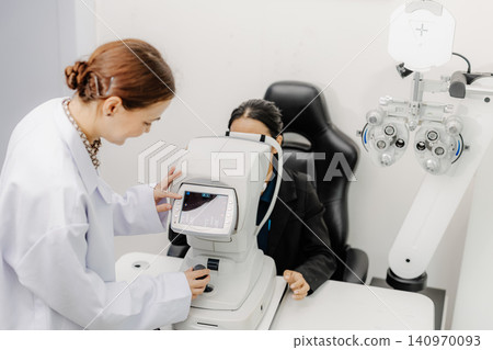 Optometrist performing eye examination with phoropter, vision test at ophthalmology clinic Optometrist performing eye examination with phoropter, vision test at ophthalmology clinic 140970093
