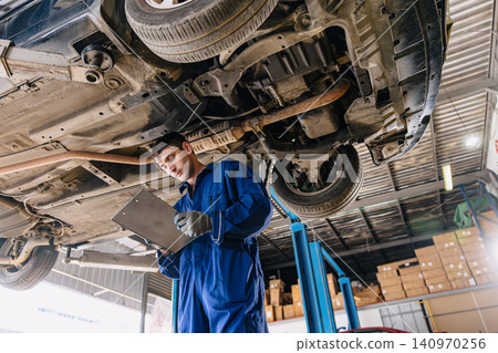 Garage Mechanic worker in auto service center working steering brake service maintenance under car. Garage Mechanic worker in auto service center working steering brake service maintenance under car. 140970256