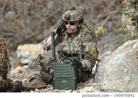 Military communications soldier operating tactical radio equipment during field mission Military communications soldier operating tactical radio equipment during field mission 140970842