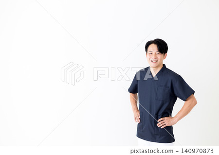 A middle-aged male doctor wearing navy blue scrubs. A middle-aged male doctor wearing navy blue scrubs. 140970873