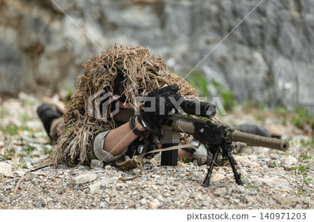 US Military marksman in camouflage ghillie suit conducting precision sniper operation US Military marksman in camouflage ghillie suit conducting precision sniper operation 140971203