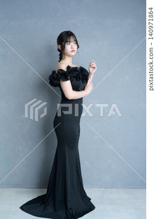 A Japanese woman in a black dress against a gray background. A Japanese woman in a black dress against a gray background. 140971864