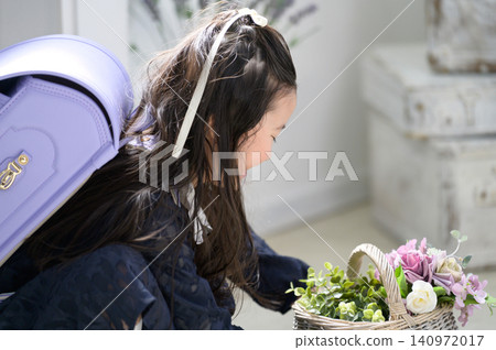 A Japanese girl with a schoolbag on her back gazes at a basket of flowers. A Japanese girl with a schoolbag on her back gazes at a basket of flowers. 140972017