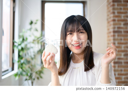 A Japanese woman eating a rice ball during her lunch break at the office. A Japanese woman eating a rice ball during her lunch break at the office. 140972156