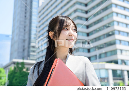 A Japanese woman holding a binder in a business district. A Japanese woman holding a binder in a business district. 140972163