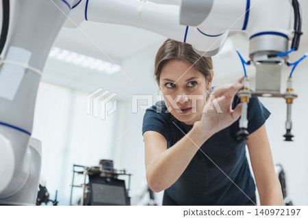 Young engineer woman working in Robotic lab test program robot prototype. Robotic factory research. Young engineer woman working in Robotic lab test program robot prototype. Robotic factory research. 140972197