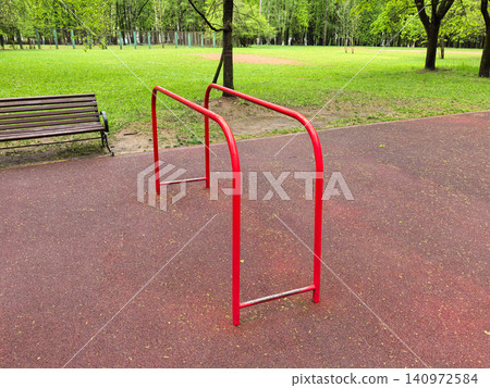 Red Parallel Dip Bars in Green Public Park Red Parallel Dip Bars in Green Public Park 140972584