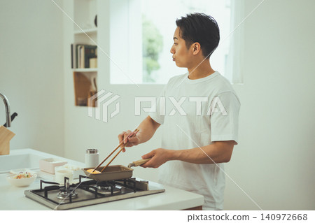 一個男人一邊抱怨一邊做煎蛋捲的側臉照。 一個男人一邊抱怨一邊做煎蛋捲的側臉照。 140972668